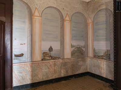 Entriamo in un vano dalle pareti decorate ad arcate, con sceniche vedute di paesaggi marini